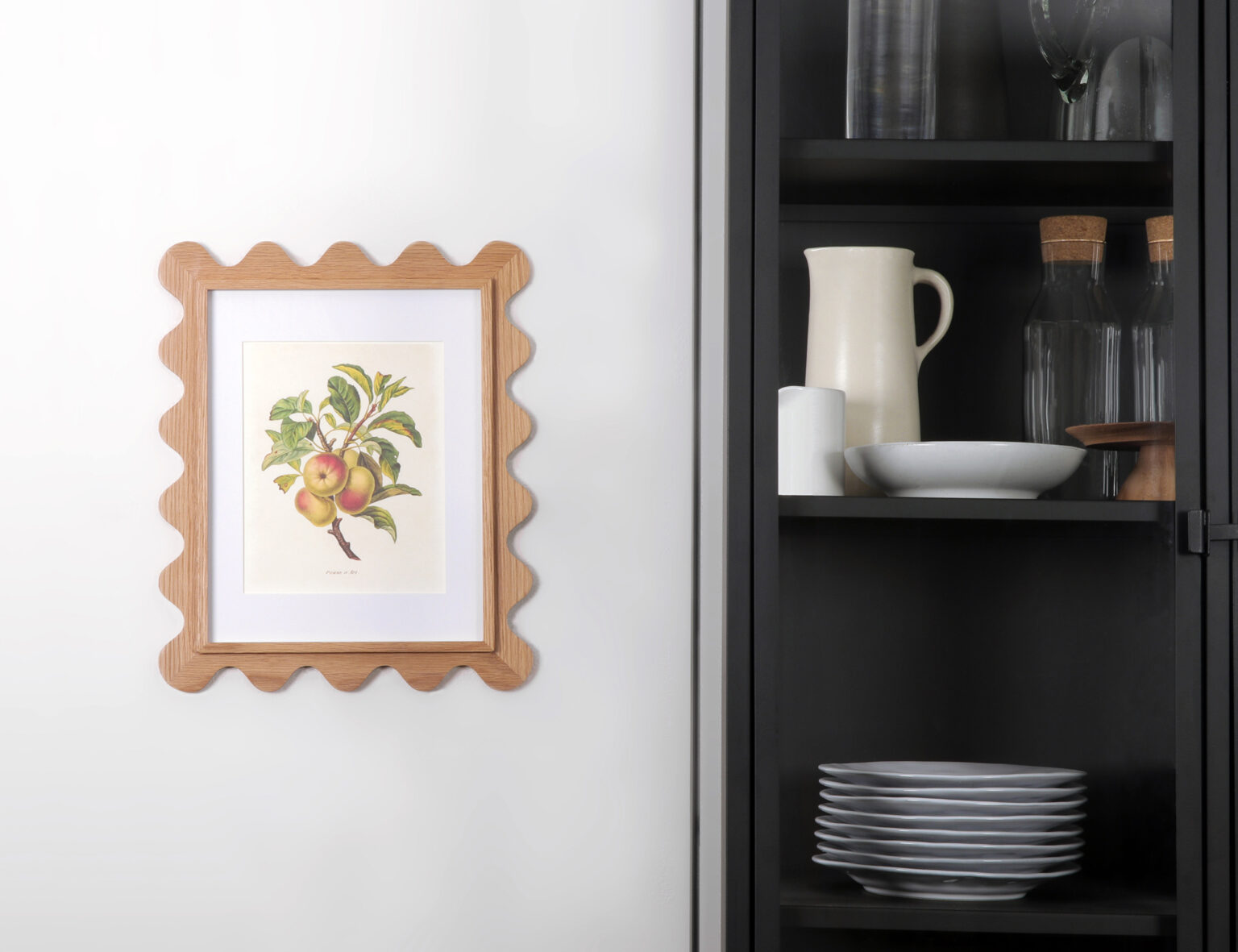 11x14 scalloped picture frame in white oak with a botanical apple print, hung next to a black cabinet