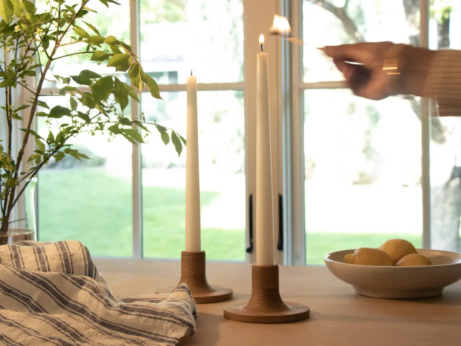 Handmade wooden taper candle holders on a table by a window