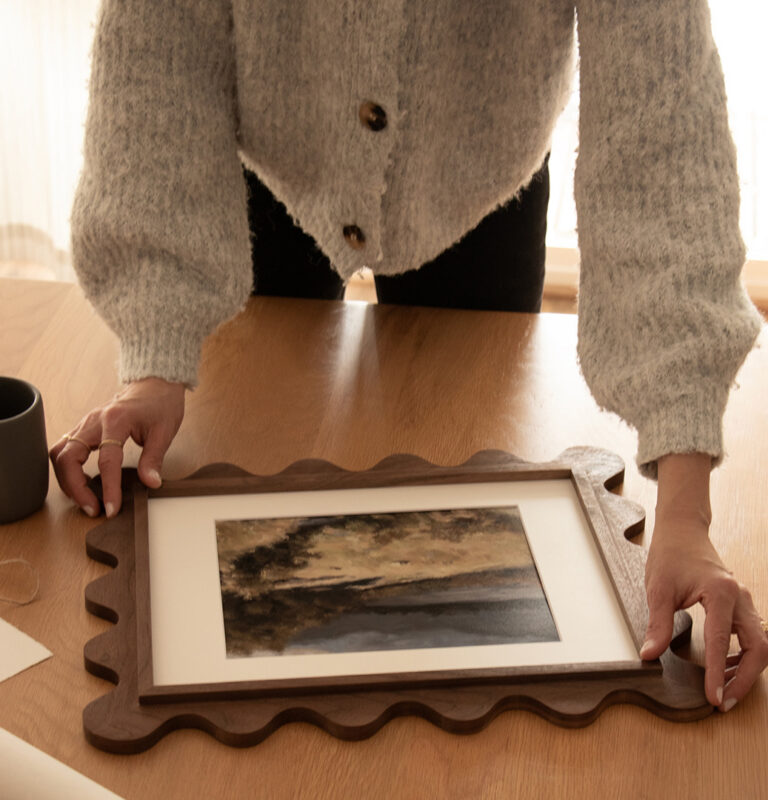Walnut 11x14 scalloped frame with a matted landscape print on a table